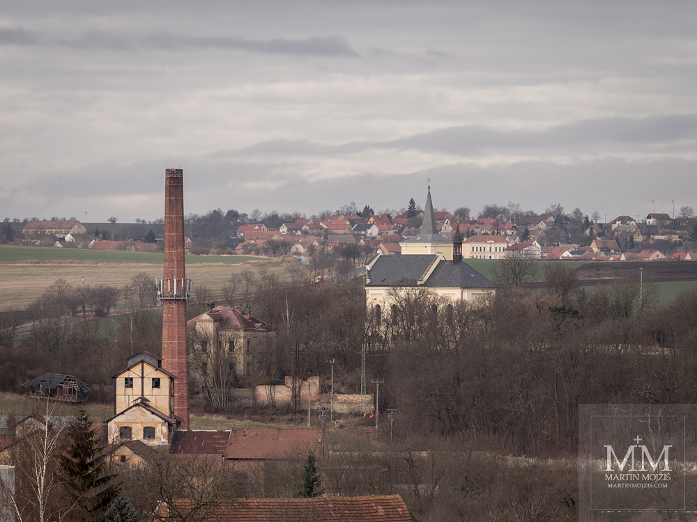 Továrna a kostel před vesnicí. Fotografie vytvořená objektivem Olympus M. Zuiko digital ED 40 - 150 mm 1:2.8 PRO.